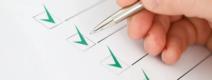 Ręka trzymająca pióro lub długopis zaznacza pola na liście